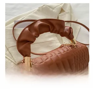 Close-up of brown crocodile pattern handbag featuring a ruched cloud handle and gold metal rings
