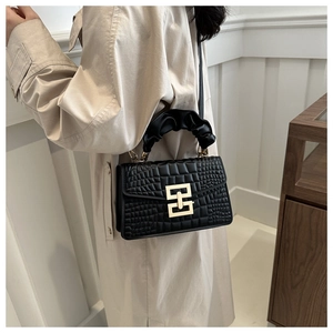 Detail of crocodile embossed leather handbag with golden geometric lock and ruffled handle