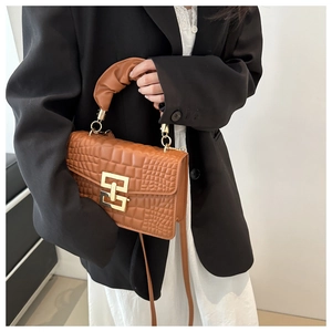 Detail of caramel crocodile pattern handbag with pleated handle and gold hardware