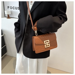 Close-up of brown crocodile texture handbag featuring a large golden H-shaped metal buckle