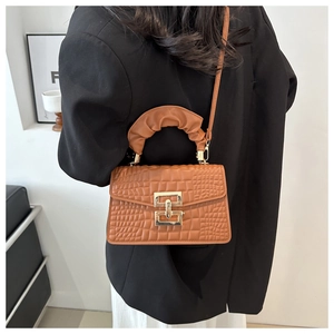 Detail view of brown crocodile texture leather bag with gold buckle and pleated handle
