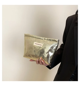 Detail of metallic gold fashion bag featuring square texture and white brand label