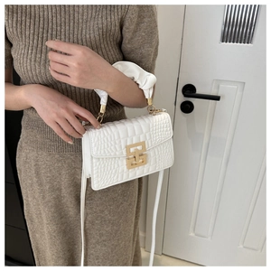 Detail of white crocodile pattern handbag with gold clasp and ruched handle detail
