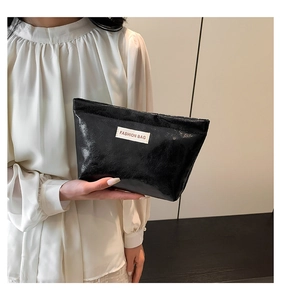 Close-up of black fashion bag showing its glossy textured leather and white label detail