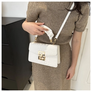 Close-up of white crocodile pattern handbag with golden twist lock and ruched handle detail