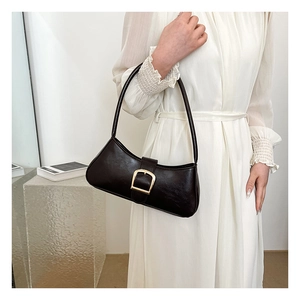 Detail view of a vintage dark brown baguette bag with a gold square buckle on a white dress