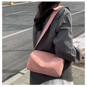Detailed shot of pink corduroy cylinder bag texture and wide strap worn by a model