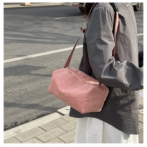 Detail of pink corduroy cylinder crossbody bag showing soft ribbed texture and adjustable strap