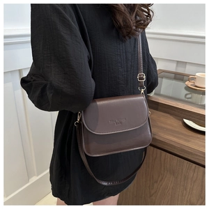 Détail du sac besace vintage en cuir marron foncé avec logo et boucle métallique