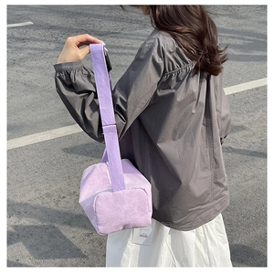 Detailed texture of lilac corduroy pillow bag with adjustable wide strap on model