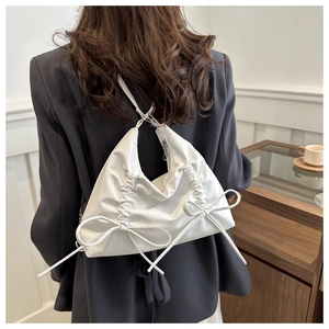 Detail of white bow decoration on soft leather shoulder bag with pleated texture