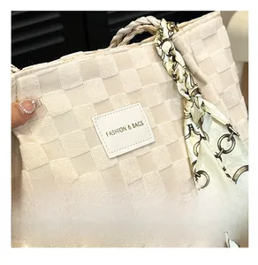 Detail der cremefarbenen Tasche mit Schachbrett-Textur und elegantem Seidenschal-Accessoire