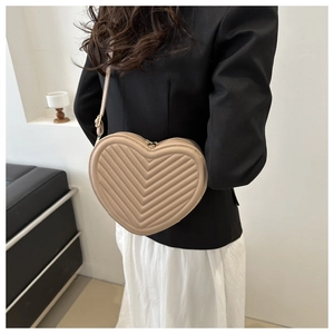 Close-up of beige heart-shaped crossbody bag with elegant V-shaped quilted embroidery detail