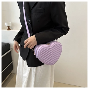 Detail of purple heart-shaped crossbody bag with V-quilted texture and gold hardware