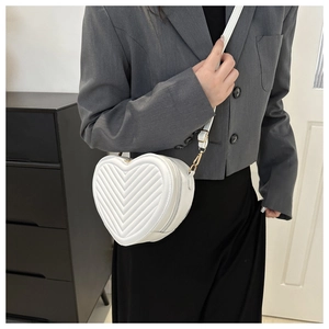 Close-up of white heart-shaped crossbody bag featuring V-quilted faux leather texture