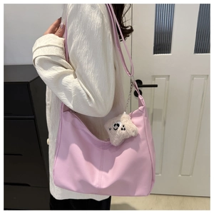 Pink PU leather shoulder bag with a cute plush monster charm shown on a model