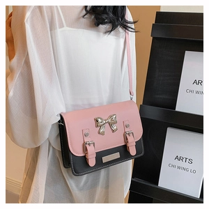 Detail view of pink and black crossbody bag with silver bow on model in casual setting