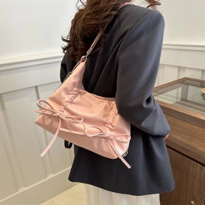 Pink minimalist tote bag with bow detail and silver chain strap shown on a model