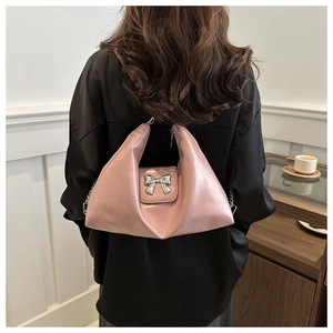 Detail of pink glossy leather tote with silver metal bow buckle worn over the shoulder