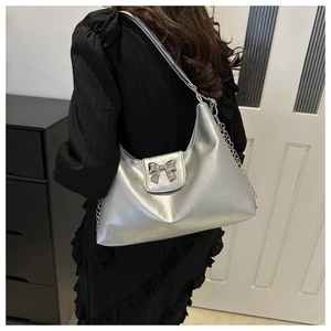 Detail of silver metallic hobo bag featuring large bow ornament and dual-style straps