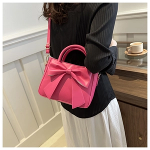 Model wearing a vibrant fuchsia mini square bag with a large bow decoration