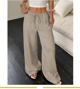 Detail of light khaki high-waisted linen trousers with drawstring waist and texture