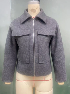 Dettaglio della giacca in lana grigio scuro con tasche grandi e chiusura a zip in metallo