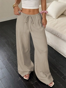 Detail of light khaki wide-leg casual pants showing drawstring waist and pleated texture