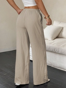 Close-up of pleated high waist texture and elastic waistband on beige wide-leg trousers