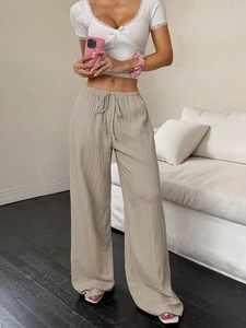 Detail of high-waist straight leg trousers with pleated texture and drawstring waist