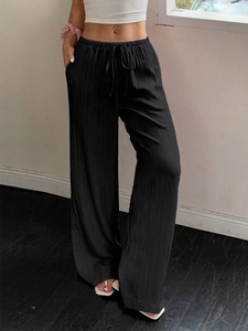 Detail of black wide-leg trousers featuring elastic drawstring waist and pleated texture