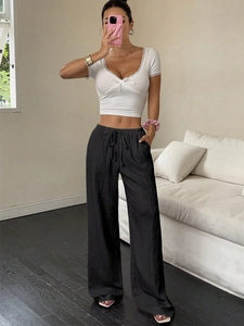 Detailed texture of black pleated wide-leg pants and white lace camisole set for women