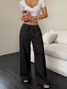 Detail of high waist black pleated trousers with elastic drawstring waistband and texture