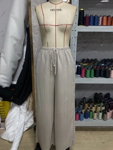 Detail of elastic drawstring waistband on beige wide leg trousers with ribbed texture
