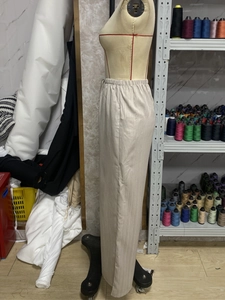 Detail of light beige vertical striped trousers with elastic waistband and soft texture