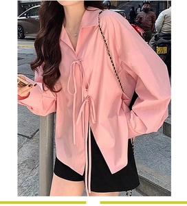 Détail d'une chemise rose à manches longues avec double fermeture à nœud et col classique