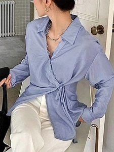 Detail of light blue wrap shirt featuring waist tie design and elegant cotton texture