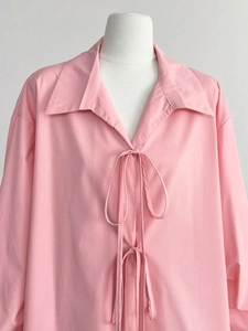 Détail de la chemise rose à manches longues avec col classique et nœud de serrage avant