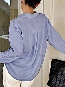 Detail of loose fit blue shirt featuring vertical pleated texture and back box pleat