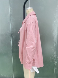 Détail d'un chemisier rose à manches longues avec col standard et fente latérale