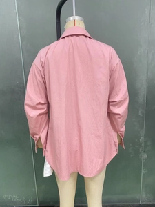 Détail de chemise rose à manches longues montrant le pli dos et l'ourlet arrondi