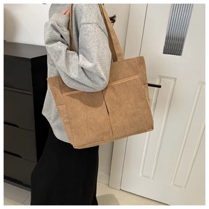 Close-up of corduroy tote bag with two front pockets and soft ribbed texture in brown
