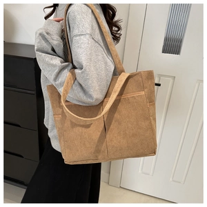 Detail view of large brown corduroy tote bag with front pocket showing fabric texture