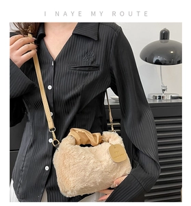 Detail of plush faux fur texture and gold pendant on beige crossbody shoulder bag