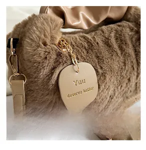 Close-up of plush faux fur texture and engraved leather tag with golden metal chain