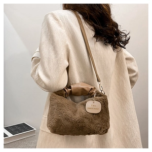 Close-up of brown plush shoulder bag featuring faux fur texture and a leather handle