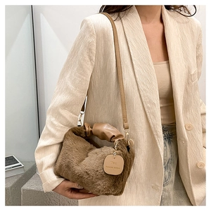 Close-up of brown plush crossbody bag with leather strap and decorative pendant detail