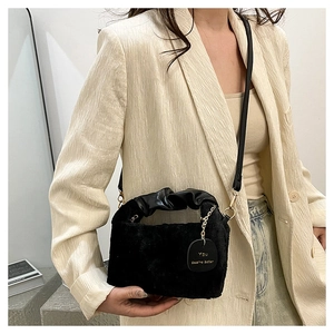 Detail of black faux fur bag with gold chain and engraved leather brand tag