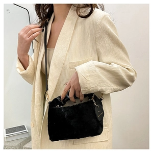 Detail view of black plush shoulder bag with golden hardware and leather strap