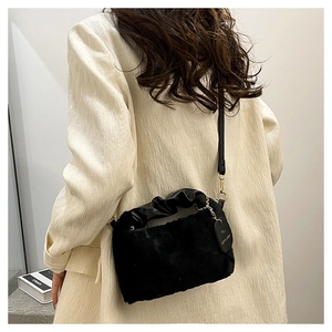 Detail of black faux fur plush crossbody bag with soft leather cloud handle and gold chain